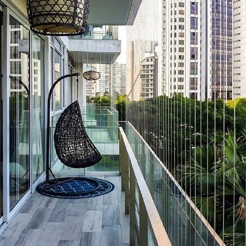 High-rise balcony secured with invisible stainless-steel wire safety grill and a hanging swing chair